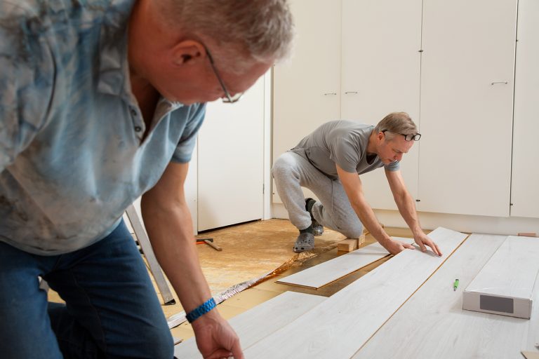 two,mature,men,installing,laminate,flooring,in,a,new,home